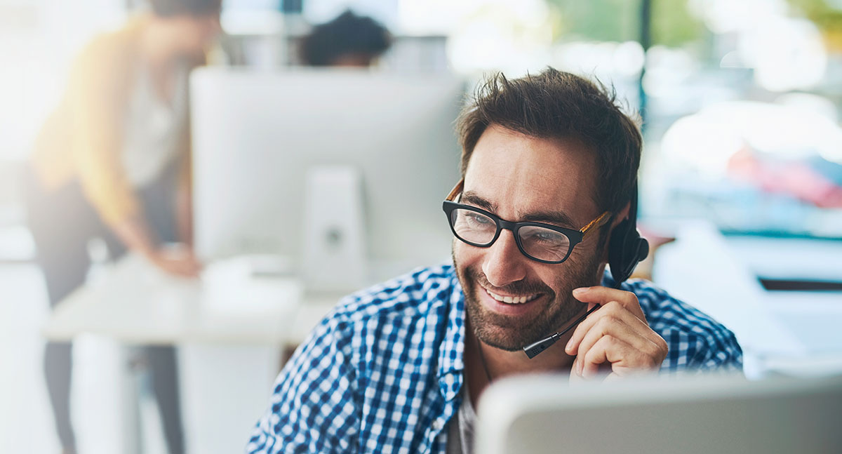 AdobeStock_1101928442 Smiling IT support specialist on the phone – tracking tickets and visualizing statuses in C2 ITSM.