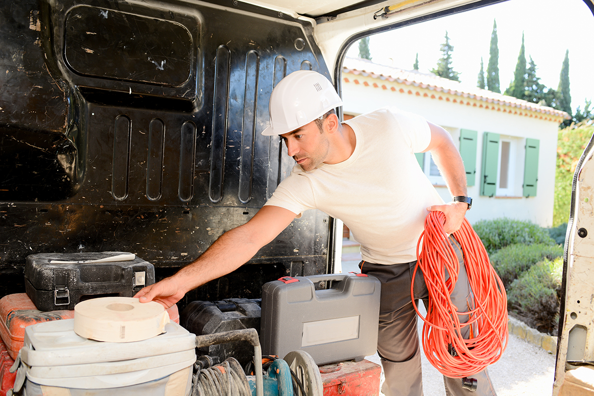young electrician artisan taking tools out of professional truck van IT technician unloading tools and cables from a service van, representing problem lifecycle tracking and root cause analysis.