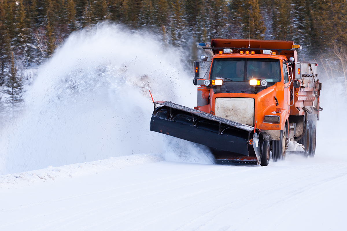 Snow plow clearing road after winter snow storm Municipal snowplow clearing a street, symbolizing asset and fleet management for public works departments using C2 ITSM.