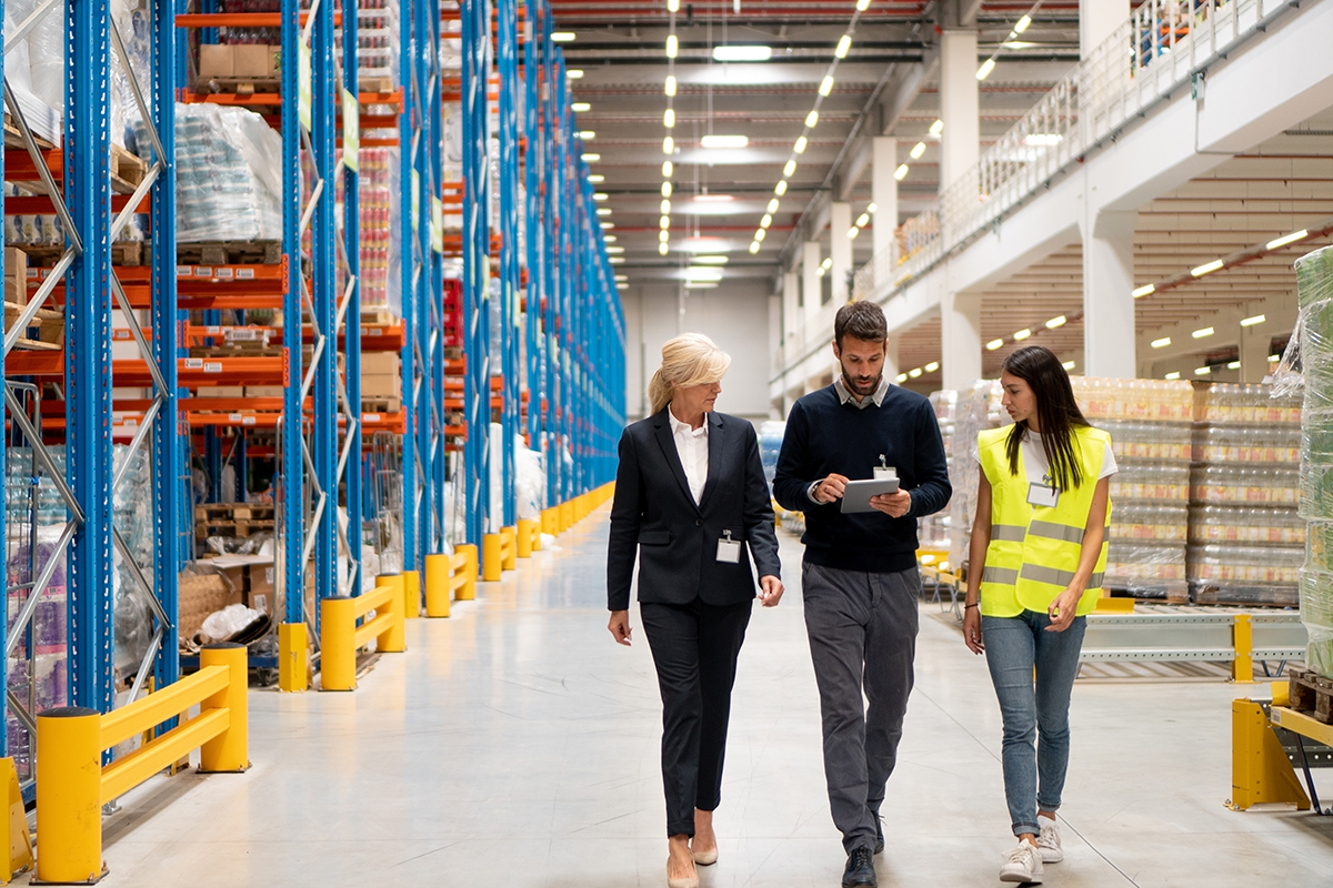 Managers visit warehouse Team walking through warehouse aisles, symbolizing visibility into asset value and lifecycle management.