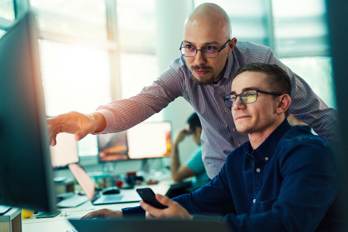 AdobeStock_213932796 Two IT professionals reviewing dashboards on a monitor, illustrating SLA tracking and service performance improvement with C2 ITSM.