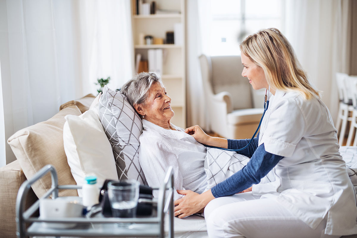 AdobeStock_245958208 A nurse gently assists an elderly patient in a bright hospital room, symbolizing compassionate care and streamlined operations powered by C2 ITSM.