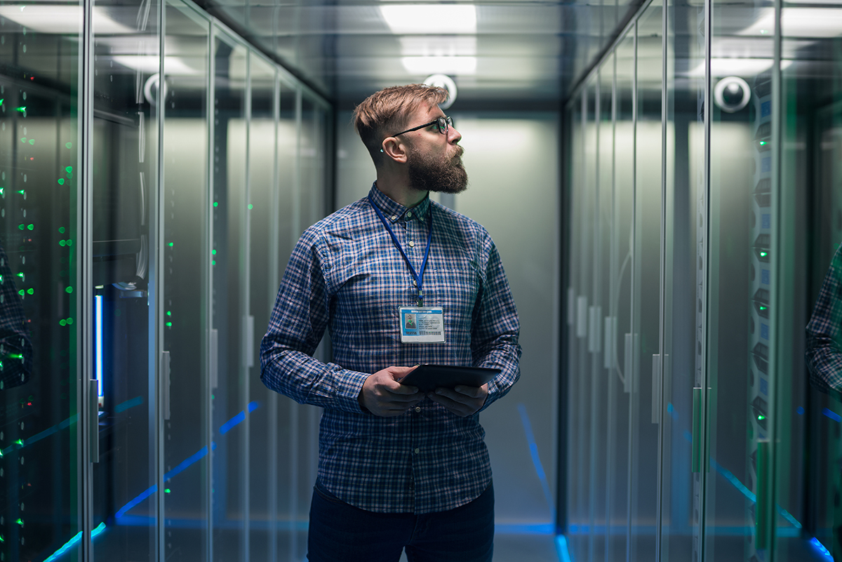 Adult bearded engineer in server room A government IT specialist inspecting data servers in a secure facility, representing organized and centralized infrastructure management with C2 ITSM.