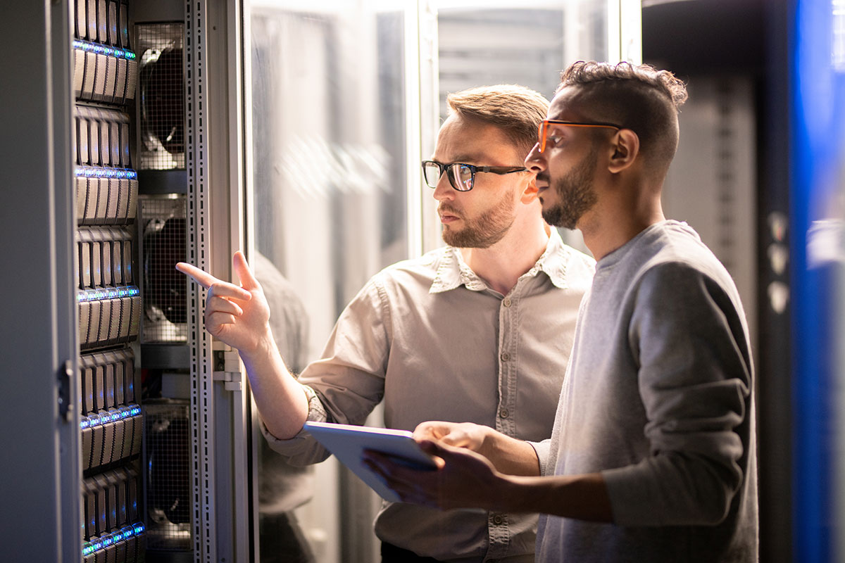 AdobeStock_271134500 Two employees inspecting shared IT equipment in a server room, representing efficient tracking and accountability.