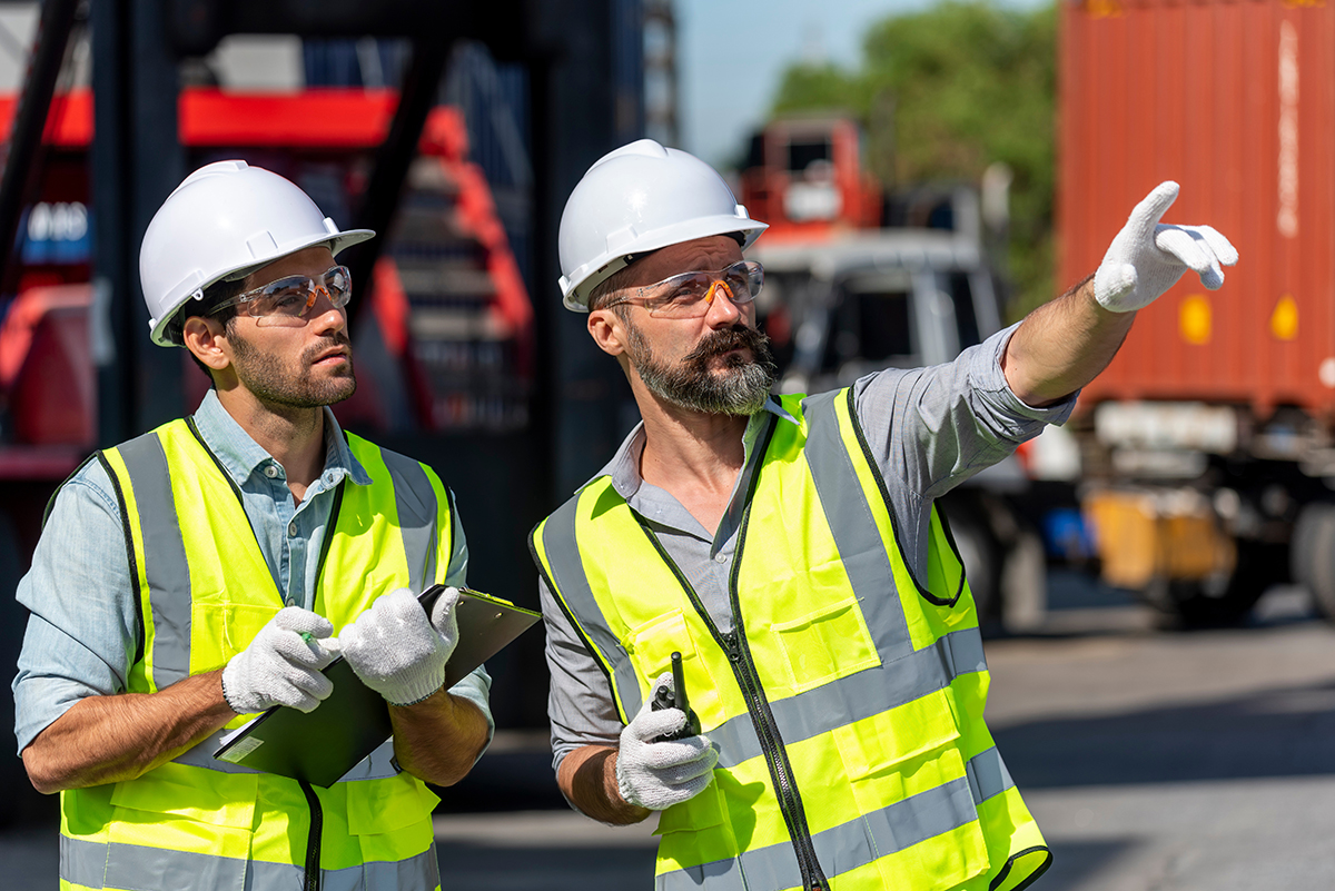 Logistics engineer and inspector working togetter and discussing Équipe sur le terrain bénéficiant d’une gestion cohérente des processus grâce à l’automatisation C2 ITSM