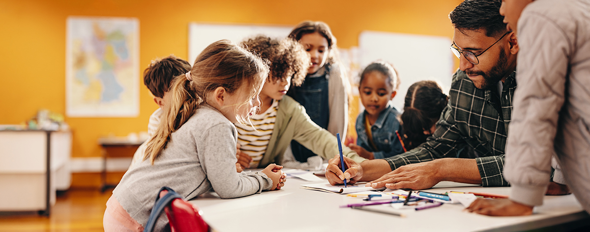 Art and creativity in an elementary school class Teacher assisting students around a table, symbolizing collaboration and centralized service management in schools.
