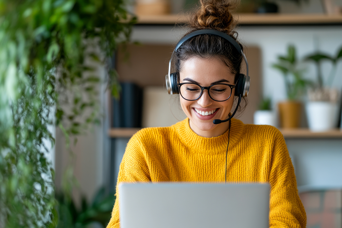 Smiling Woman in Headset Working on Laptop from Home User performing a flexible search in the C2 ITSM service desk to track tickets and verify history.