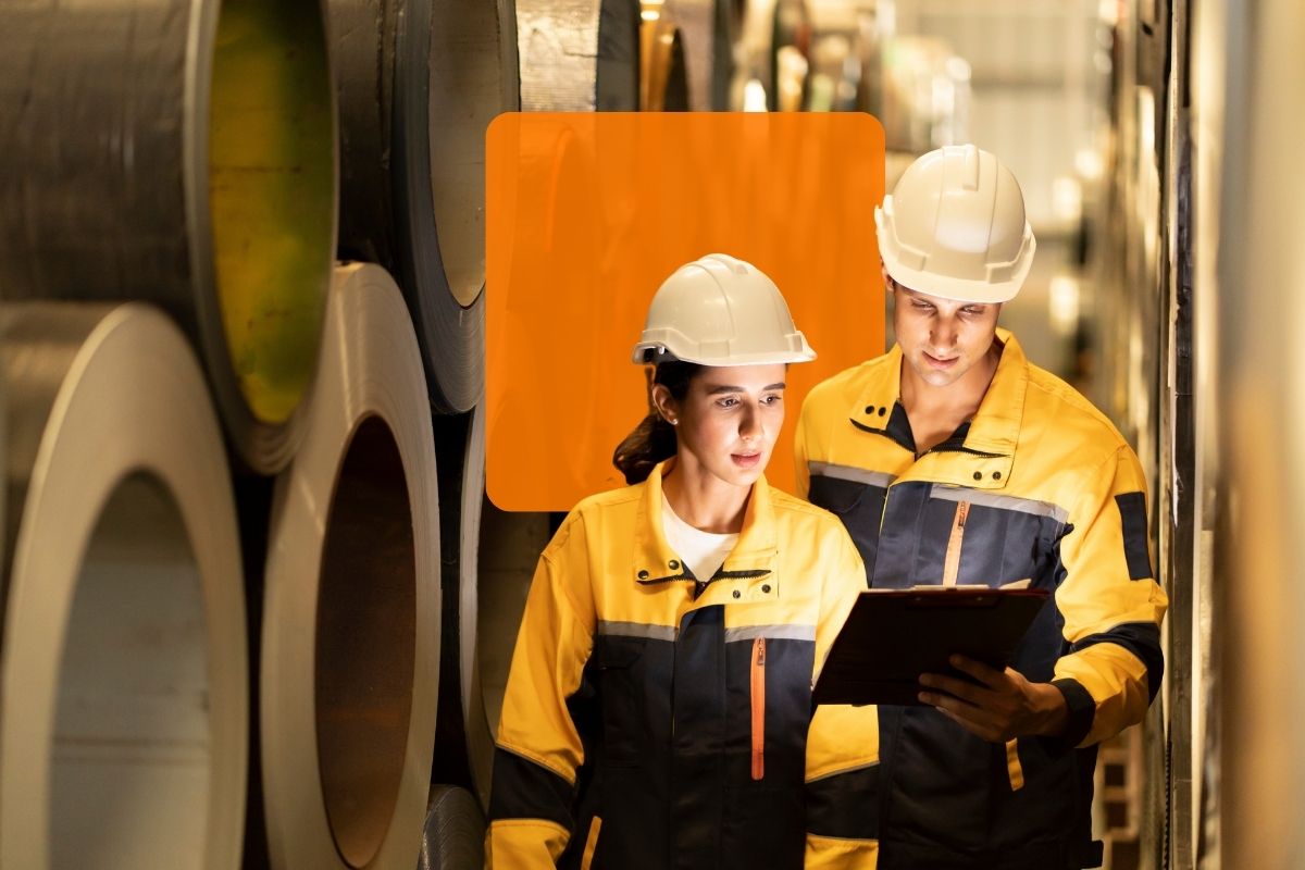 incident et probleme Two IT technicians in protective gear reviewing incident data on a tablet in a factory setting, illustrating C2’s problem management features.